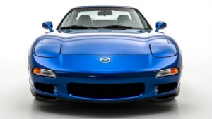 Professional studio photograph of 1995 Mazda RX7 FD generation sports car in metallic blue, showcasing sleek aerodynamic body lines, pop-up headlights, and distinctive rotary-engine hood design from three-quarter front angle, pristine condition, showroom lighting